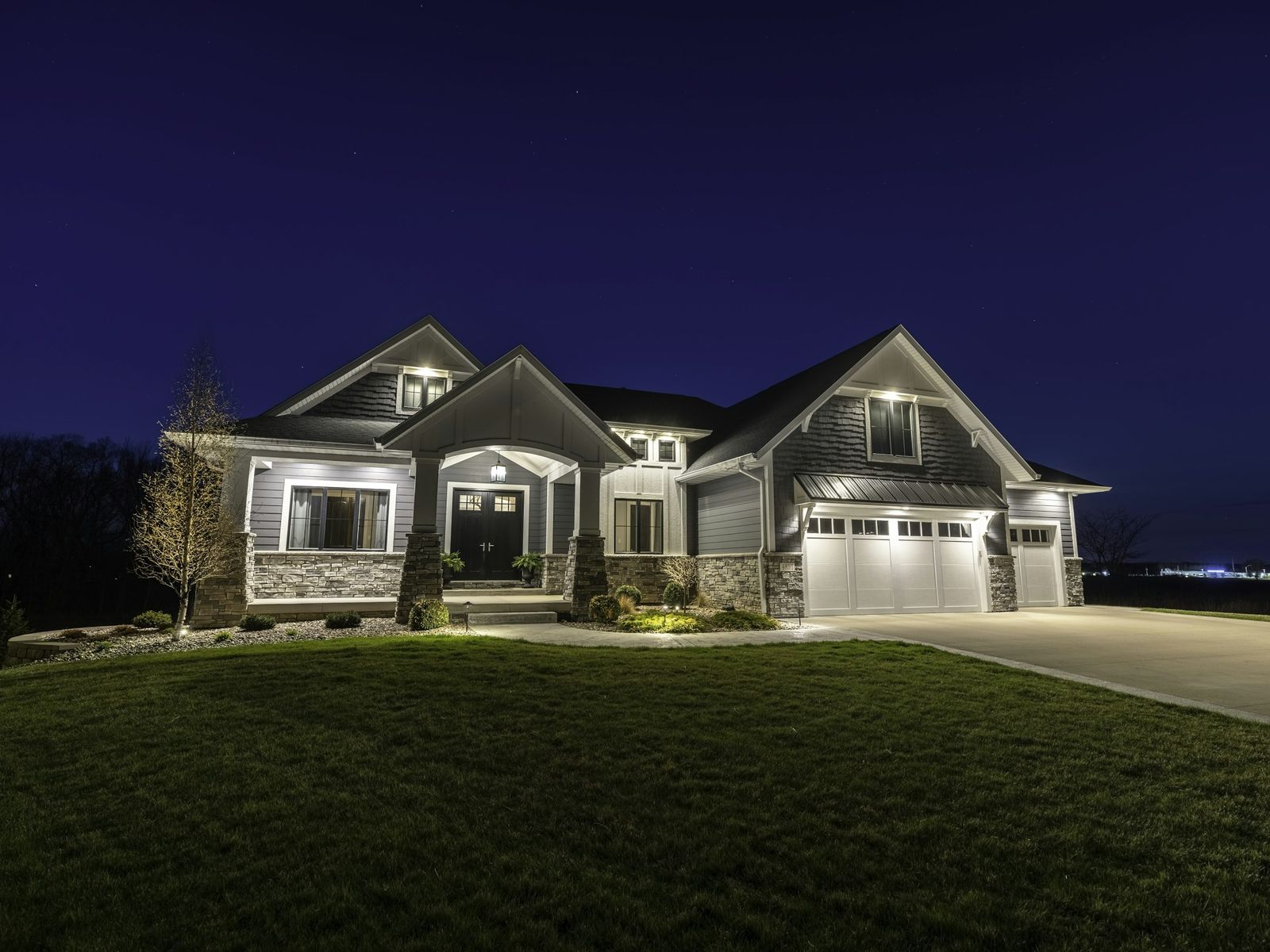 A shingle-style home lit up at night