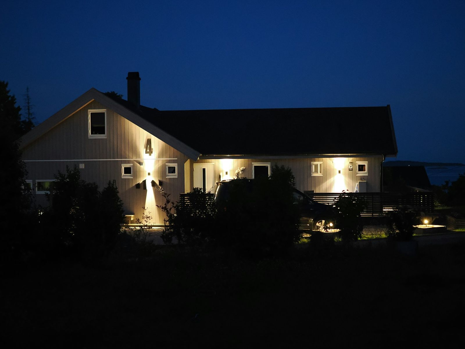 A lawn, trees and entry lit at night
