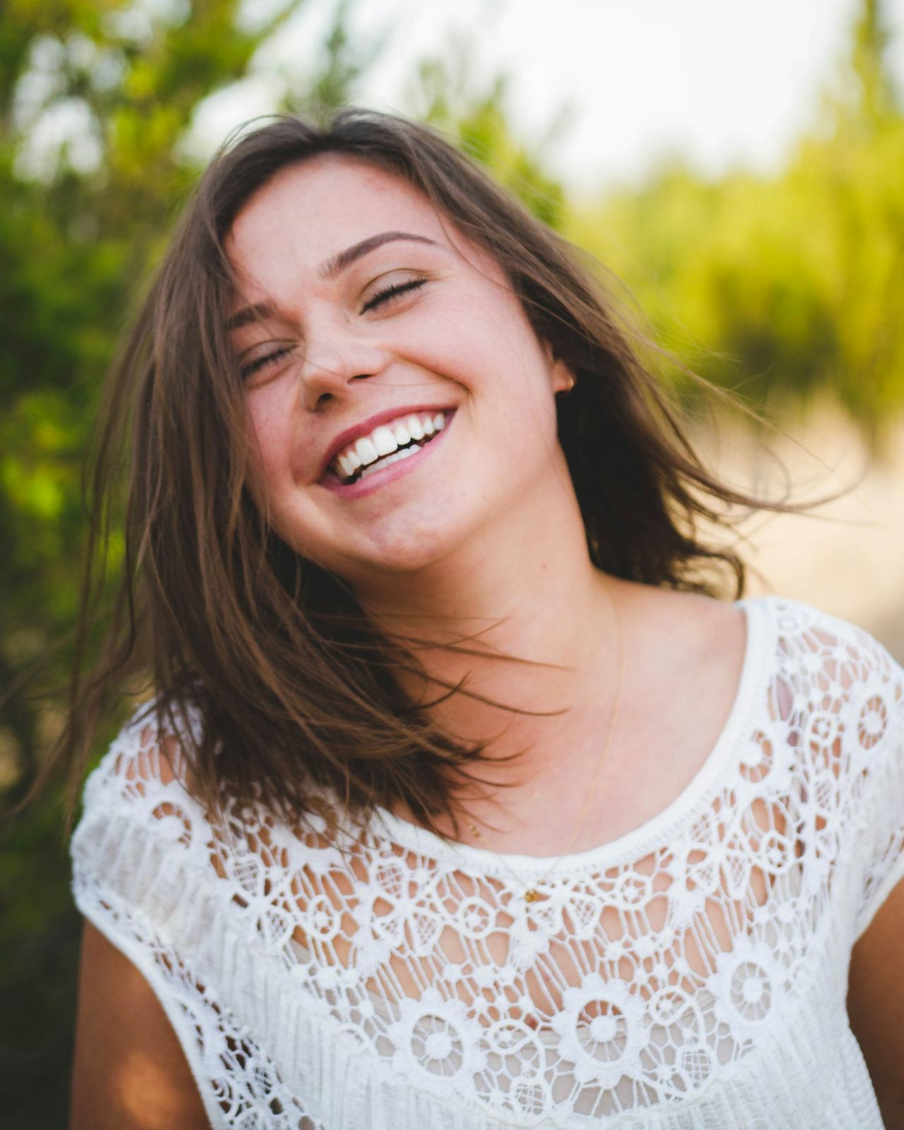 A woman laughing outdoors