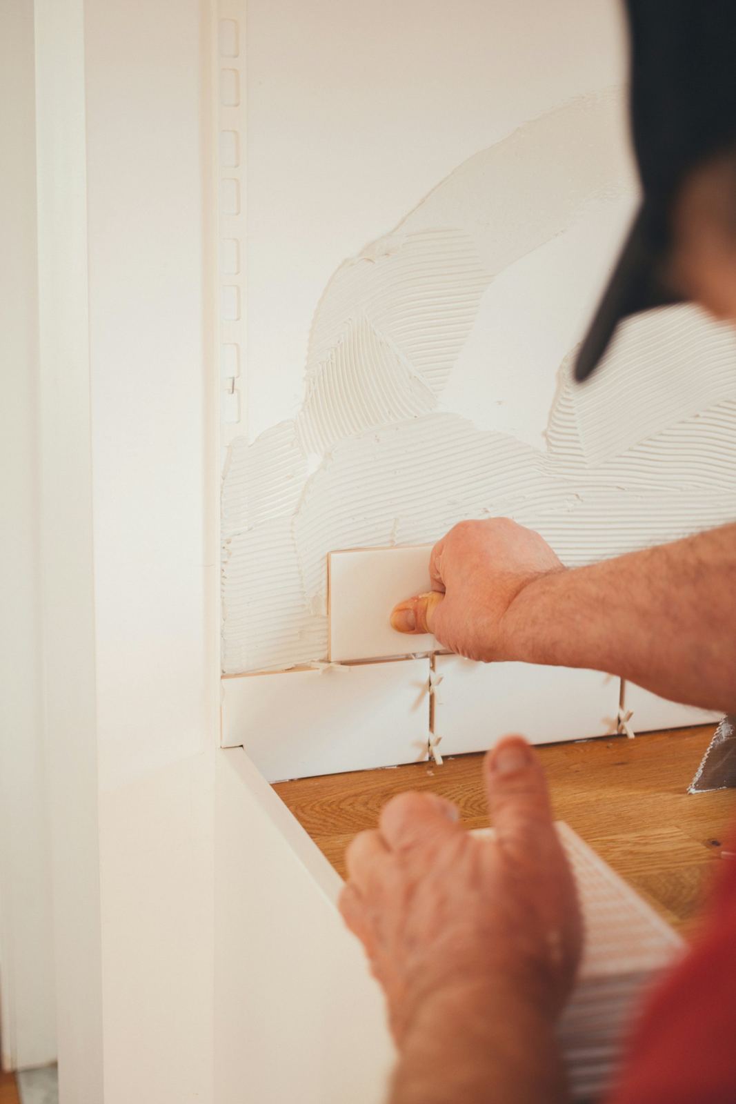 A worker fitting new drywall beside a door frame