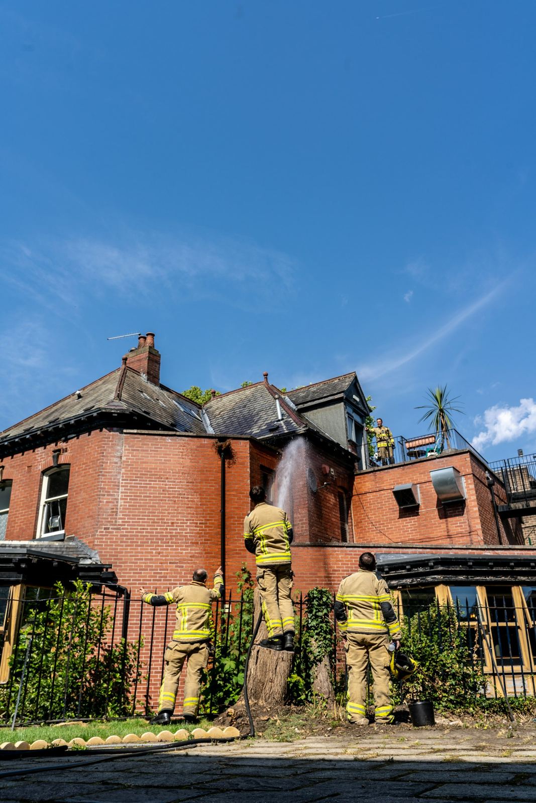 Firefighters outside a fire-damaged brick house