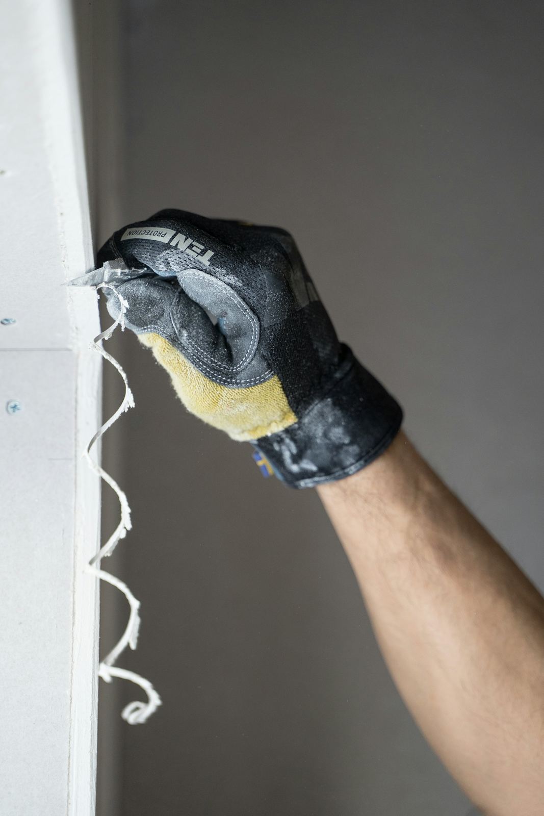 A gloved hand painting a wall with a roller