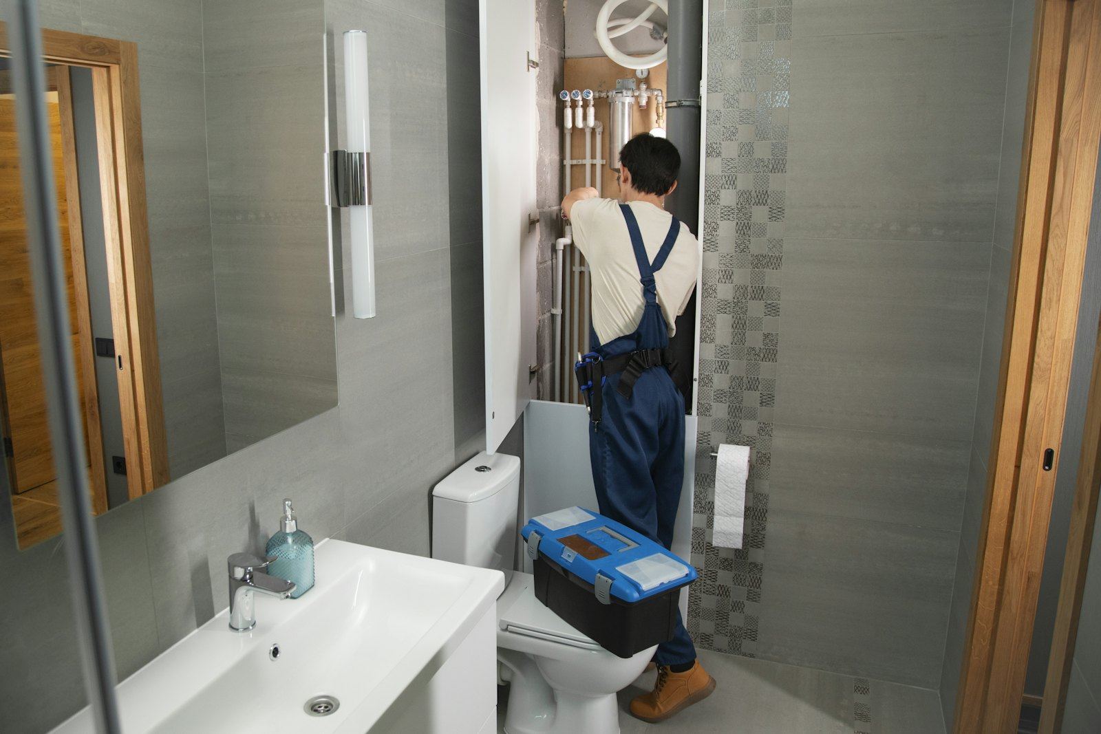 A plumber carrying a toolbox into a bathroom
