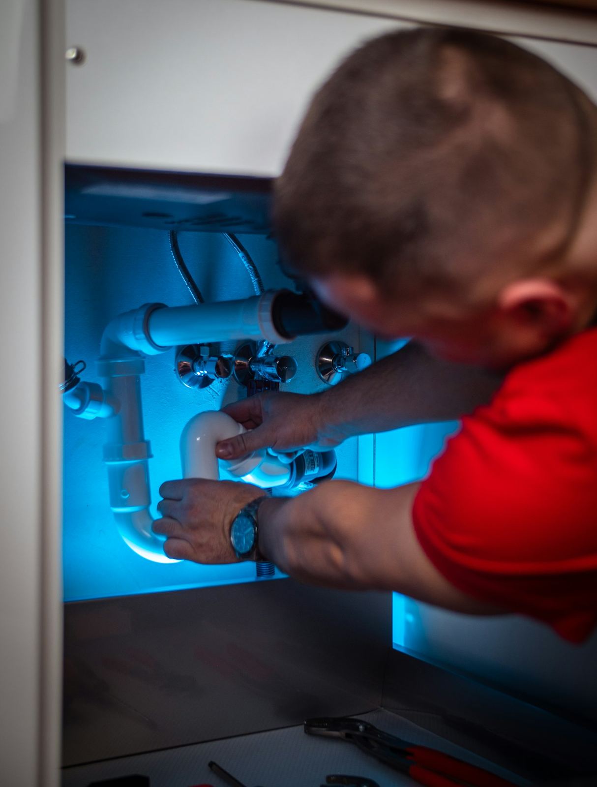 A plumber working inside a vanity cabinet