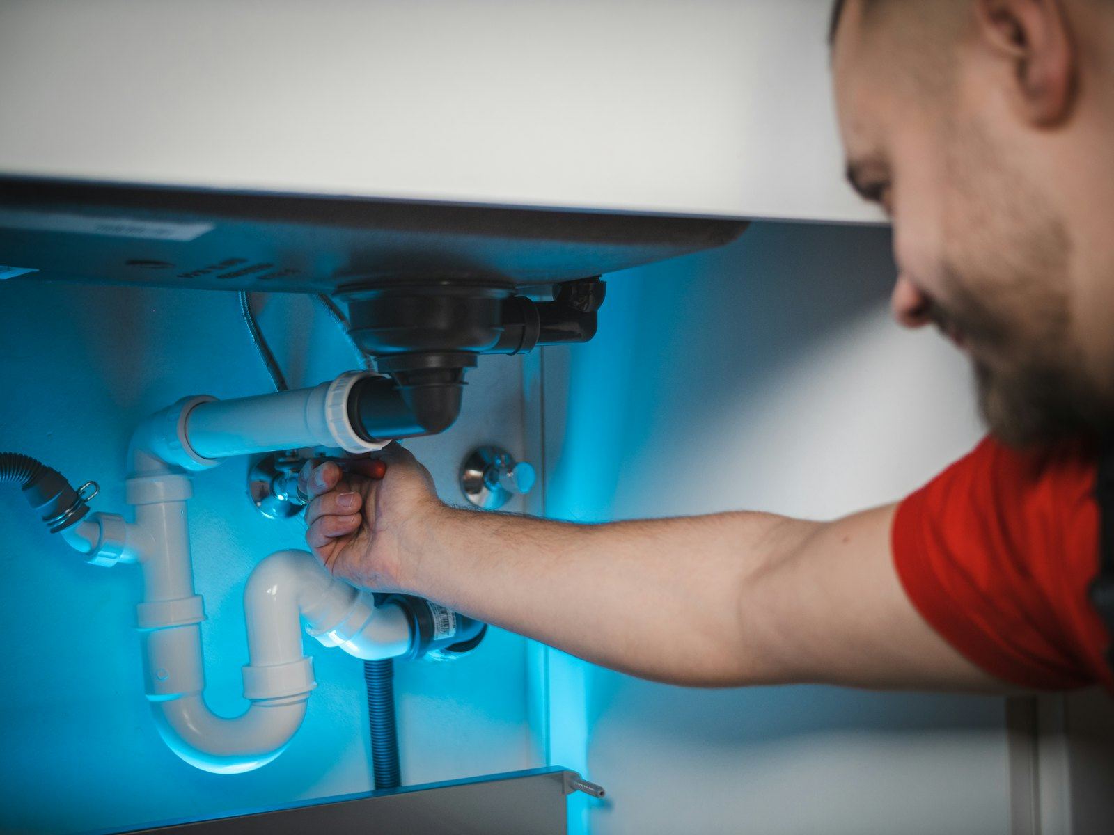 A plumber fitting a drain under a bathroom sink